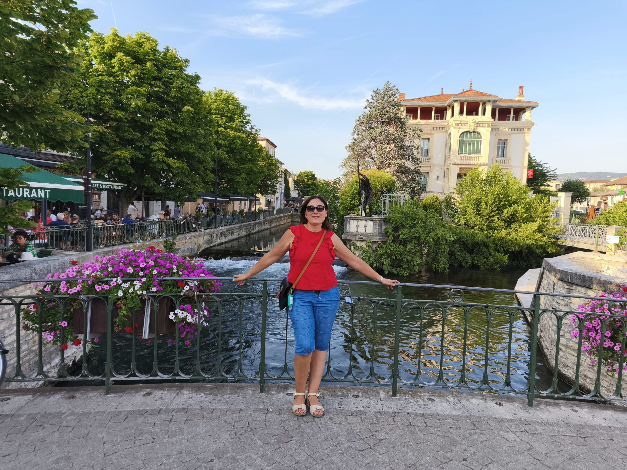 Persona su un ponte fiorito affacciato su un canale, simbolo di un viaggio alla ricerca della felicità.
